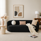 Curved black bouclé sofa with solid teak wood frame in modern living room