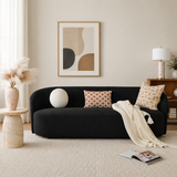 Curved black bouclé sofa with solid teak wood frame in modern living room