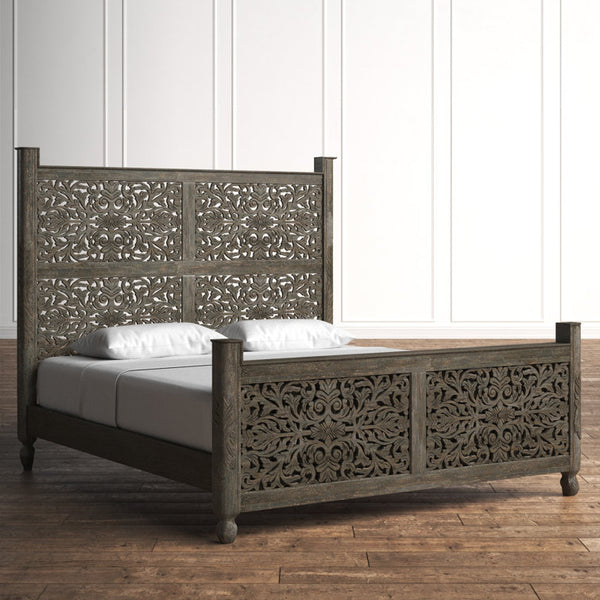 ​Close-up of intricate floral carvings on grey wood headboard.